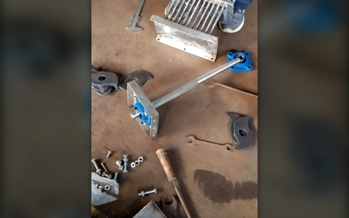 Composter agitator shaft with plummer block bearings, granulator knife set and drive parts laid out on the workshop floor before assembly
