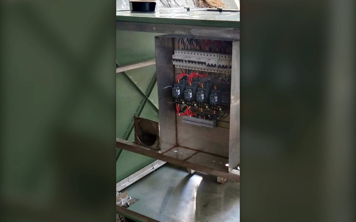 Stainless steel composter frame with the electrical control panel open, showing MCBs, contactors and wiring during fabrication at the TGMC workshop