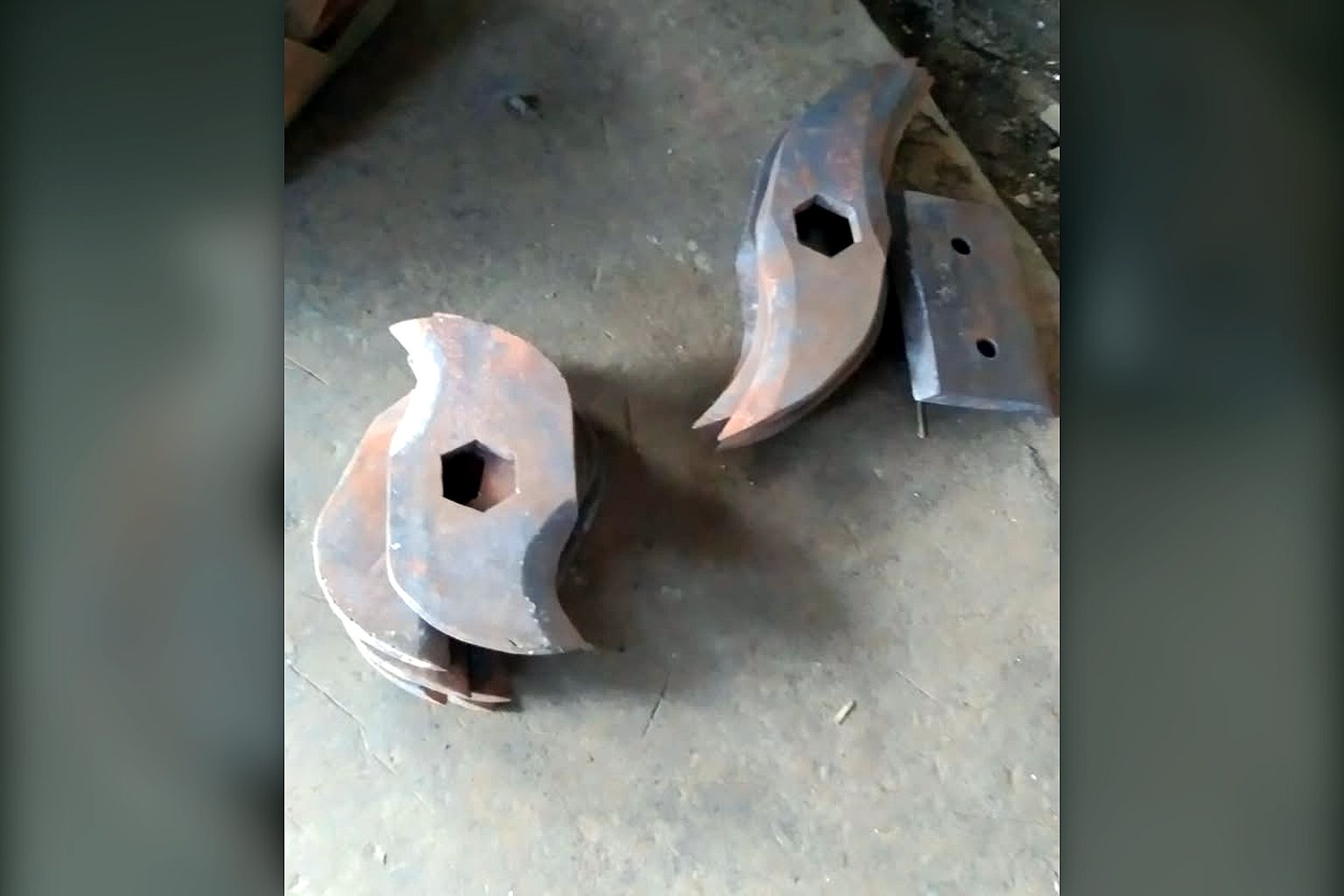 Two hooked steel shredder cutter discs with hexagonal bores on the workshop floor before fitting to a TGMC composter shredder shaft