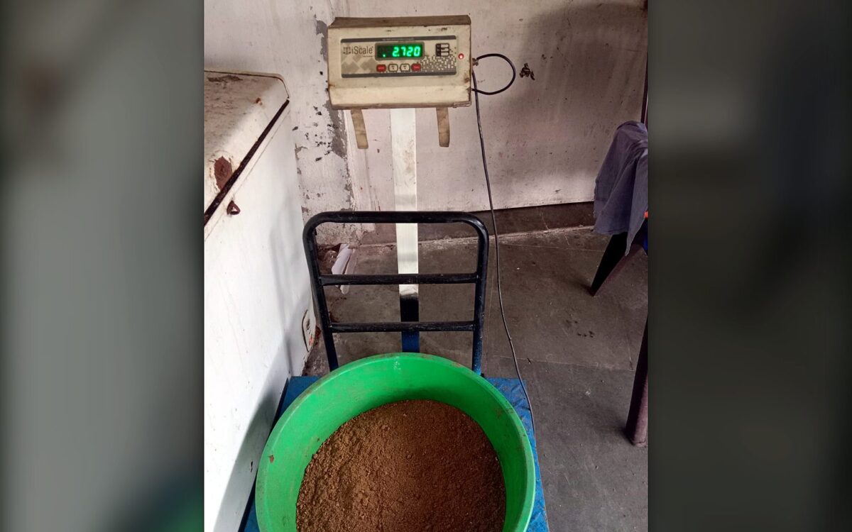 A tub of material being weighed on a platform weighing scale with a digital readout at the TGMC workshop