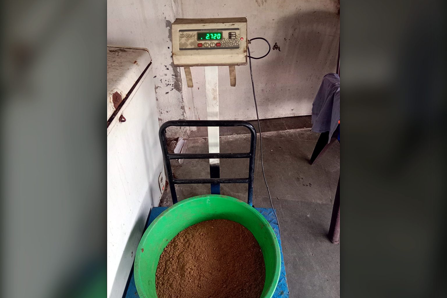 A tub of material being weighed on a platform weighing scale with a digital readout at the TGMC workshop